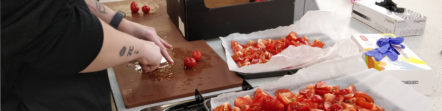 Person chopping tomatoes on a chopping board